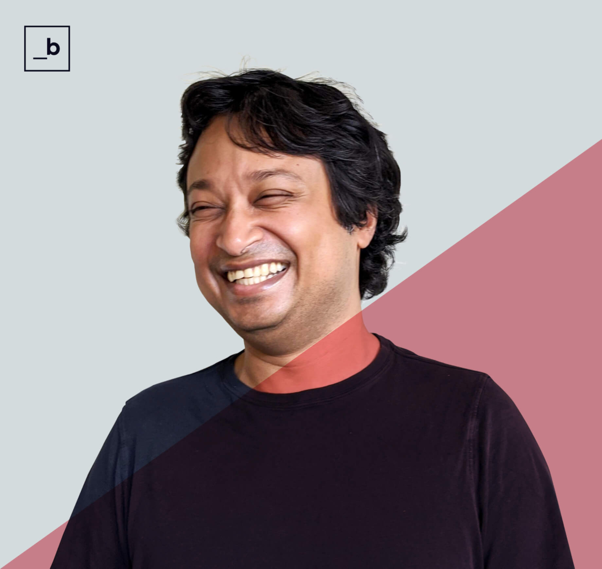Man in black shirt smiling and looking off to his right.